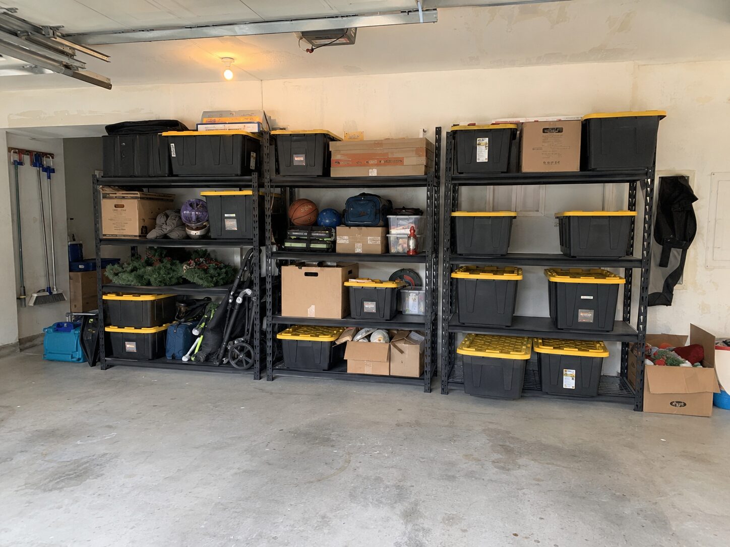 A naturally organized family garage with freestanding heavy-duty shelves and storage boxes